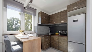 Eine moderne Küche mit Holzschränken, einem eingebauten Backofen und einem Edelstahlkühlschrank.
