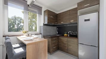 Une cuisine moderne avec des meubles en bois, un four encastré et un réfrigérateur en acier inoxydable.