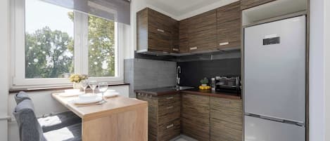 Una cocina moderna con armarios de madera, horno empotrado y refrigerador de acero inoxidable.