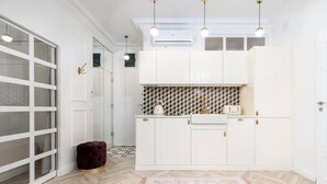 A modern kitchen with white cabinetry, a patterned backsplash, and pendant lighting. - Boutique Palais de Cracovie • 2BR • Elevator & A/C (Kraków)