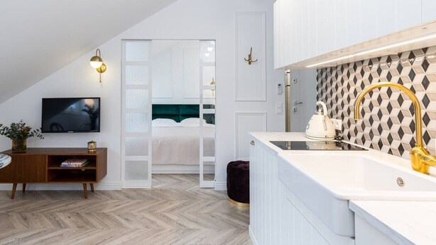 A modern bedroom with a bed, a TV, and a wooden dresser. - Boutique Palais de Cracovie • 2BR • Elevator & A/C (Kraków)
