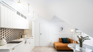 A modern kitchen with white cabinets, a herringbone-patterned backsplash, and pendant lighting. - Boutique Palais de Cracovie • 2BR • Elevator & A/C (Kraków)