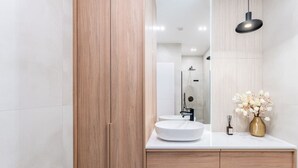 Een moderne badkamer met een houten wastafelmeubel, een rond wastafel en een spiegel.
