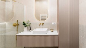 Un bagno moderno con doccia, lavandino e specchio.