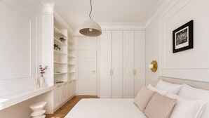 Una camera da letto con un letto grande, pareti bianche, un armadio e una lampada a sospensione.