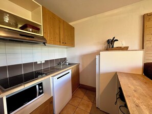 Eine kompakte Küche mit Geschirrspüler, Backofen und kleinem Kühlschrank.