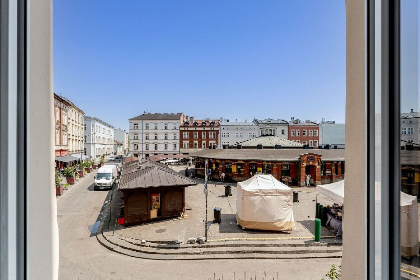 Une vue de rue avec des immeubles, un fourgon blanc et une tente.