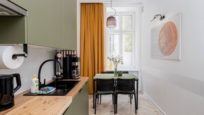 Una cocina compacta con encimera de madera, cafetera y comedor con mesa y sillas.