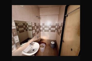 A compact bathroom with a sink, mirror, and tiled walls. - Leisurely Abode Service Apartments and Homestay (Pune)