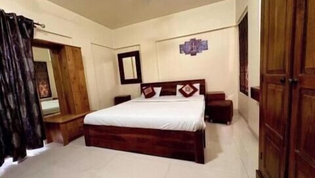 A bedroom with a wooden bed, a nightstand, a mirror, and a wardrobe.