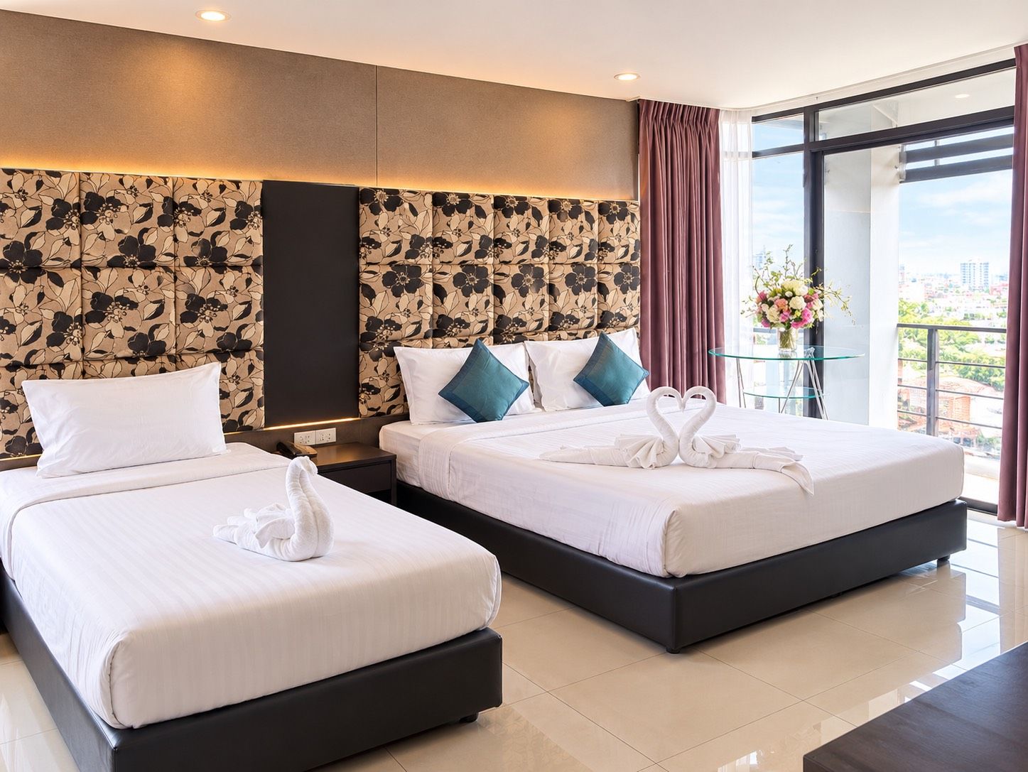 Habitación de hotel con dos camas, un ventanal grande y vistas a la ciudad.