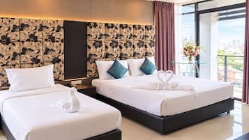 Habitación de hotel con dos camas, un ventanal grande y vistas a la ciudad.