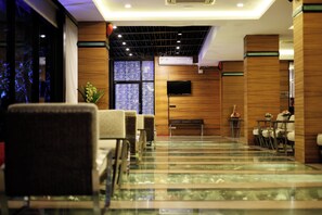 A hotel lobby with a reception desk, seating area, and a large window with a view. - Starlight Hotel Pattaya  Le Vernissage (Pattaya)