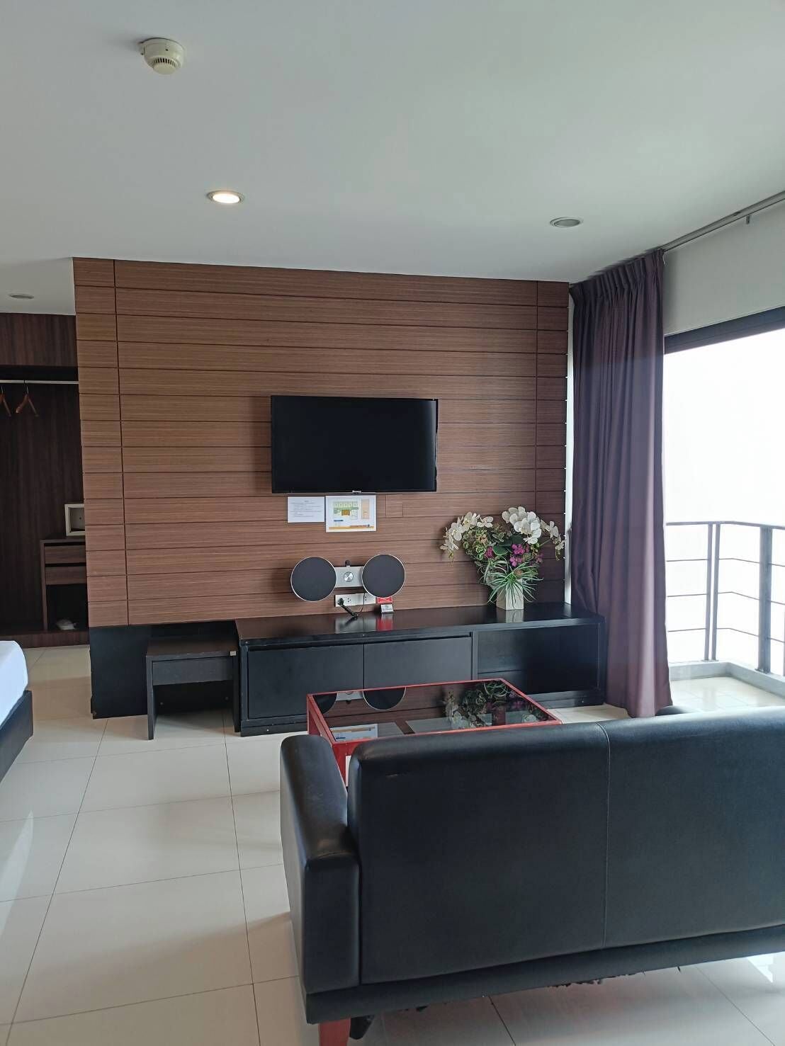 A modern living room with a flat-screen TV mounted on a wooden wall, a sofa, a coffee table, and a small side table.