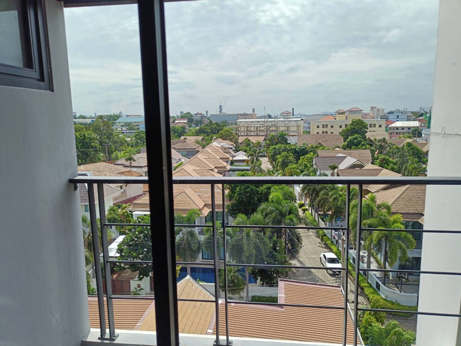 A residential area with multiple houses, a clear sky, and a view through a window with a balcony railing.