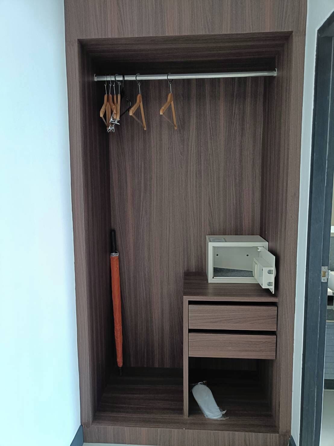 A wardrobe with a hanging rod, a shoe rack, and a small table with a printer.