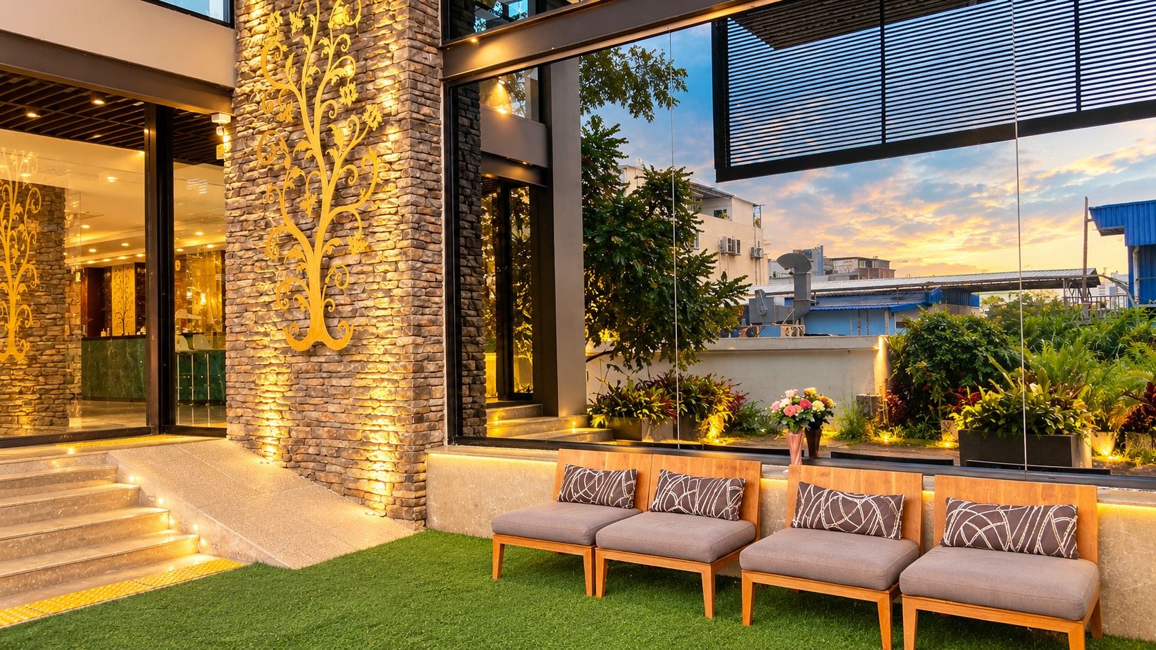 A modern building with a stone facade, outdoor seating area, and a view of the cityscape.