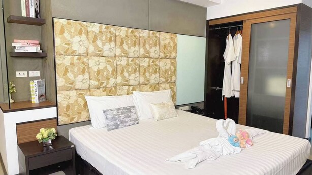 Habitación de hotel con cama, armario, mesita de noche y estante con libros.