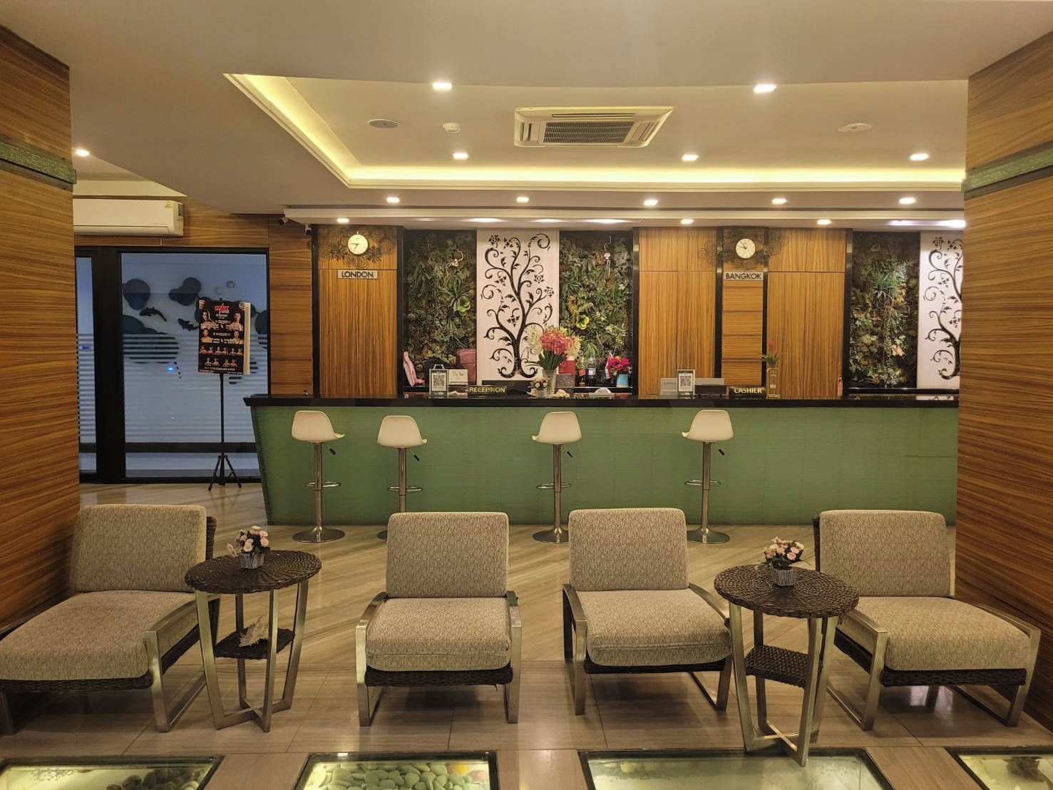 A reception area with a green counter, four chairs, and a wall with 'LONDON' and 'BANGKOK' signs.