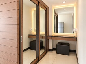 A modern bathroom with a wooden panel wall, a large mirror, a countertop with a hairdryer, and a small black stool. - Starlight Hotel Pattaya  Le Vernissage (Pattaya)