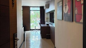 Un pasillo de hotel con una puerta de madera, una zona de comedor con mesa y sillas, y obras de arte en las paredes.