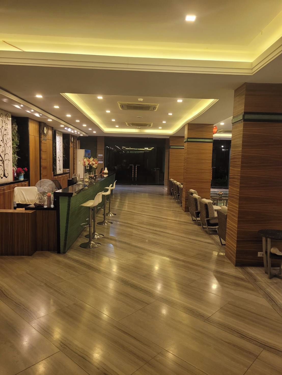 Vestíbulo de hotel con recepción, área de bar y asientos.