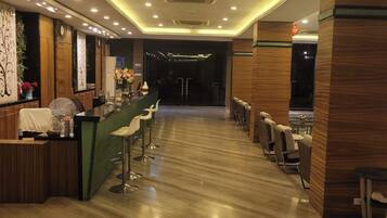 Vestíbulo de hotel con recepción, área de bar y asientos.