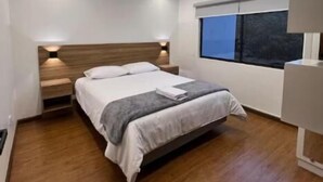 A modern bedroom with a bed, bedside tables, a window, and a ceiling light fixture.