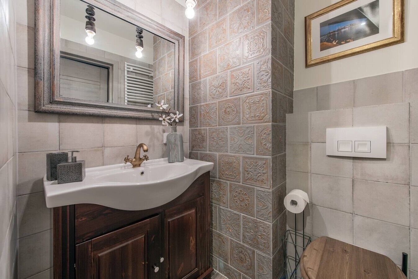 Un baño con tocador, lavamanos, espejo y azulejos decorativos.