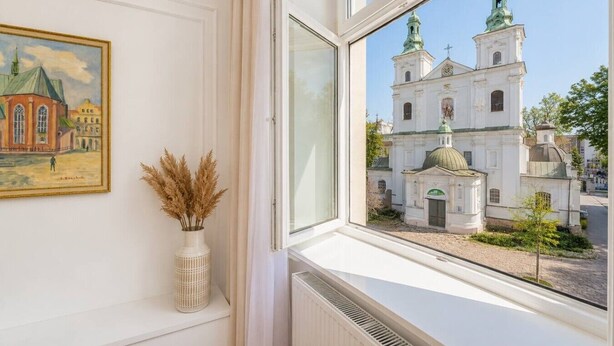Ein Fenster mit Blick auf eine weiße Kirche mit grünen Kuppeln und einem kleinen Glockenturm.