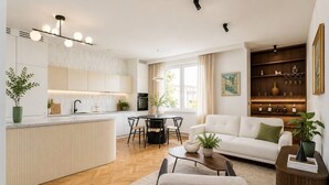 Een moderne keuken met een eetgedeelte, een woonkamer met een bank en salontafel, en een boekenkast met decoratieve objecten.