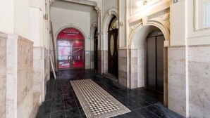 Un pasillo con alfombra a cuadros, una puerta roja con la leyenda 'WAX MUSEUM' y un piso de mármol.