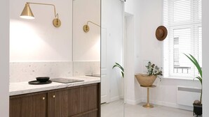 Ein modernes Badezimmer mit Marmorplatte, goldenem Wasserhahn, wandmontiertem Spiegel und einem Blumentopf.
