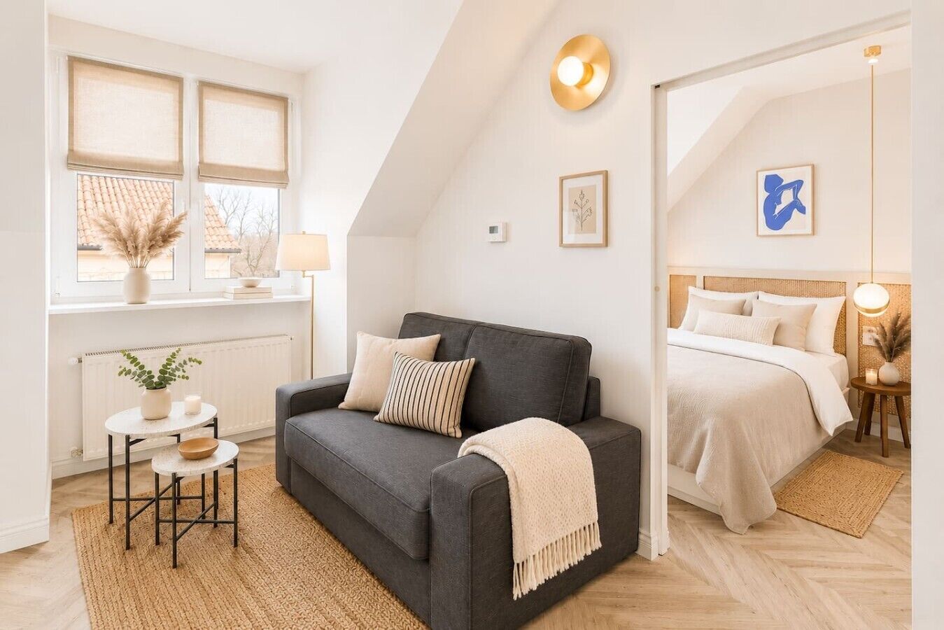 Quarto moderno com um sofá cinza escuro, uma cama de solteiro, uma pequena mesa com uma planta e um radiador.