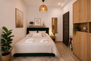 Un dormitorio con cama, mesita de noche, lámpara, planta en maceta y armario.