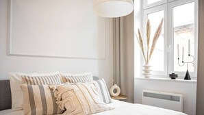 Un dormitorio con cama, ventana con vistas, radiador y lámpara.