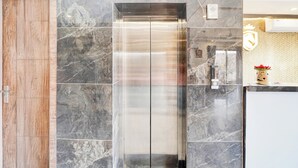 A modern elevator with a metallic finish, surrounded by marble tiles. - Super Townhouse Taj Mahal East Gate (Agra)