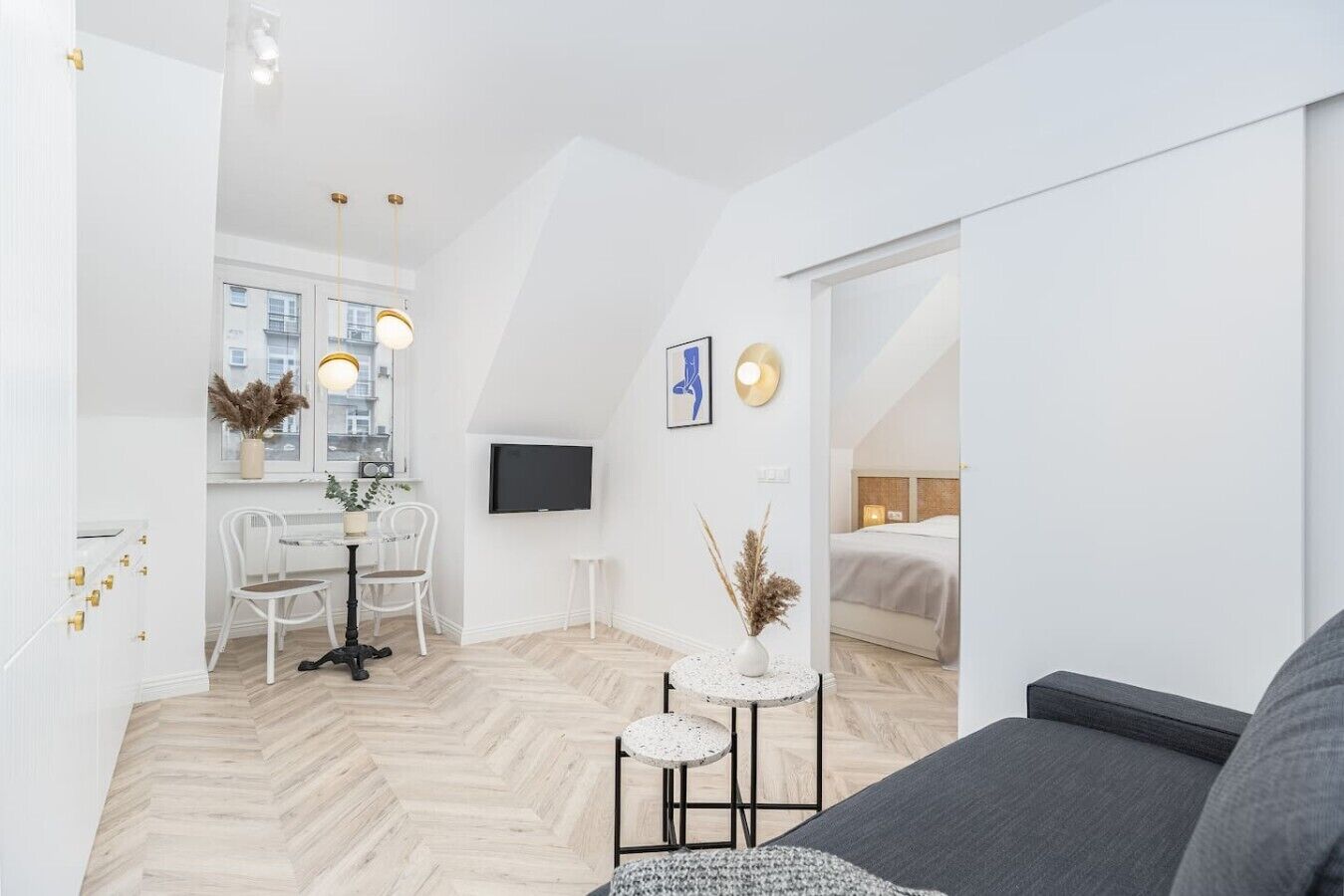 A modern, well-lit apartment with a dining area, a TV, and a bed.