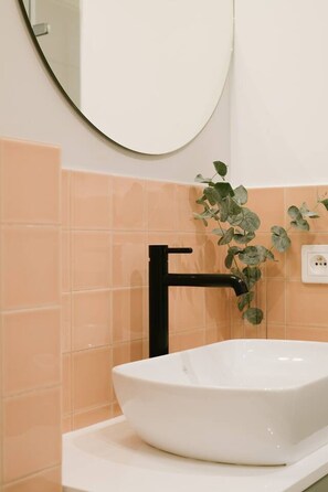 Ein Badezimmer mit einem weißen Waschbecken, einem schwarzen Wasserhahn und einem Spiegel darüber.