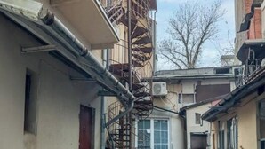 Een smalle straat met kinderafval, met gebouwen met balkons en een centrale trap.