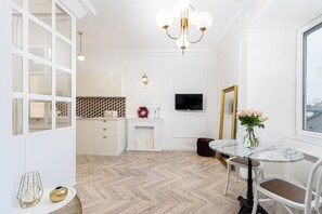 A modern interior with a herringbone wood floor, a dining area with a marble table, and a large mirror. - Heiritage Suite • 1BR • Lift & A/C • Main Square (Kraków)