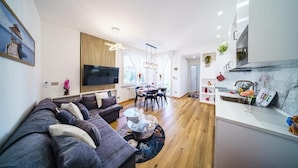 Een moderne woonkamer met een bank, eettafel en keukenhoek.