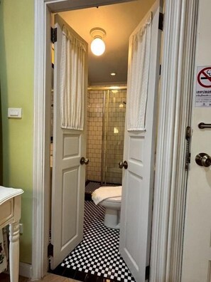 A bathroom with a checkered floor, a toilet, and a shower area. - Maison Dang Boutique Hotel (Chiang Mai)