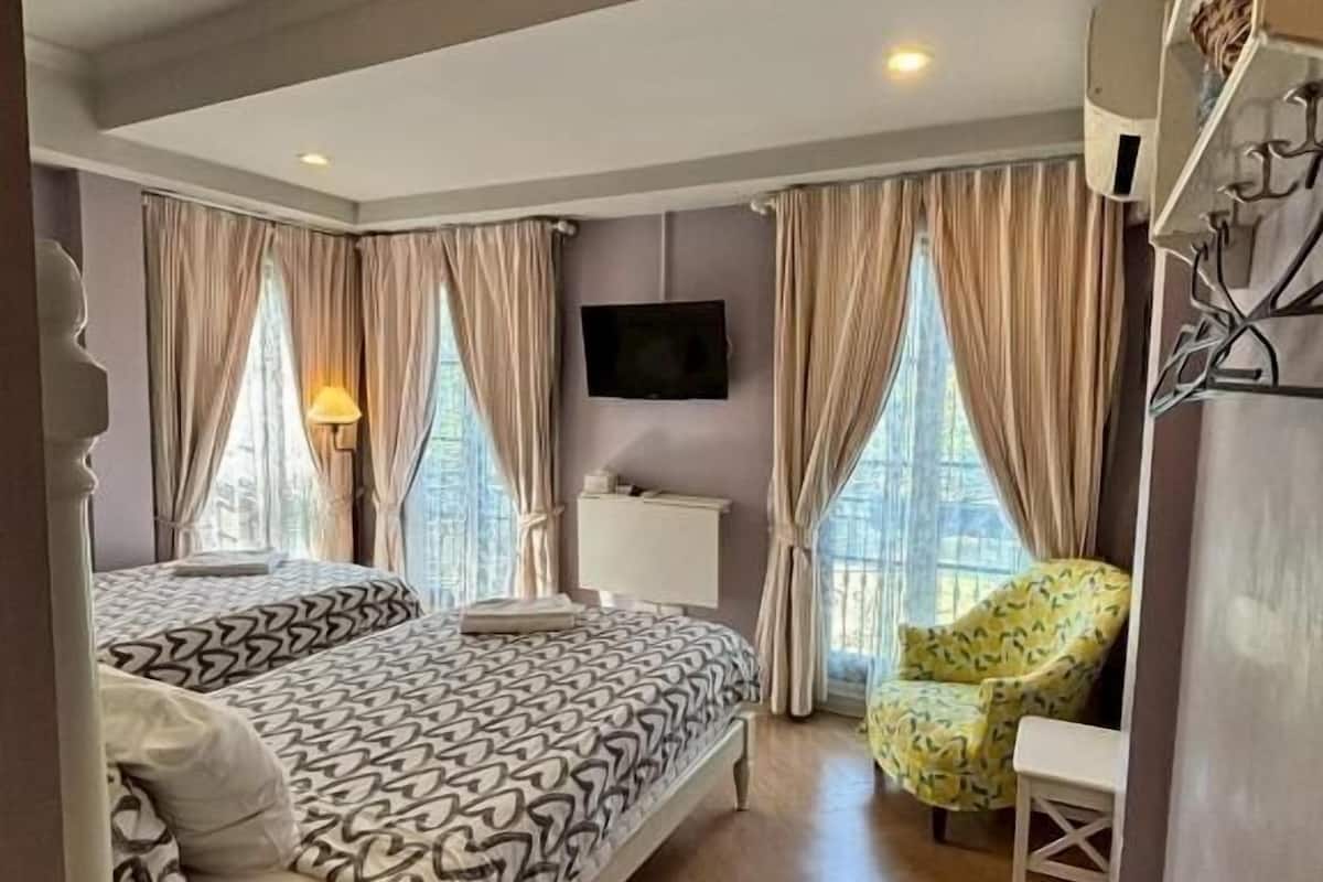 Un dormitorio con cama, una silla, un televisor y ventana.