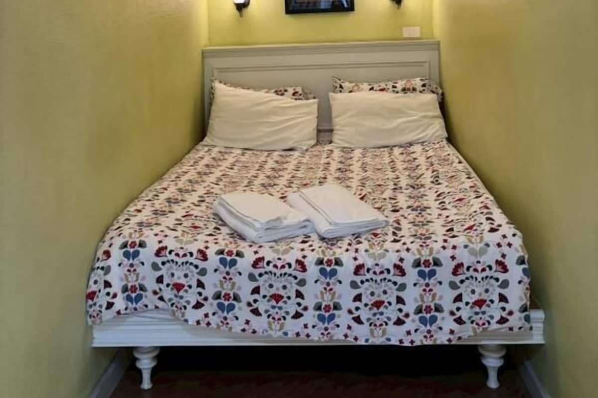 Una cama con colcha estampada, dos almohadas y cabecero blanco.