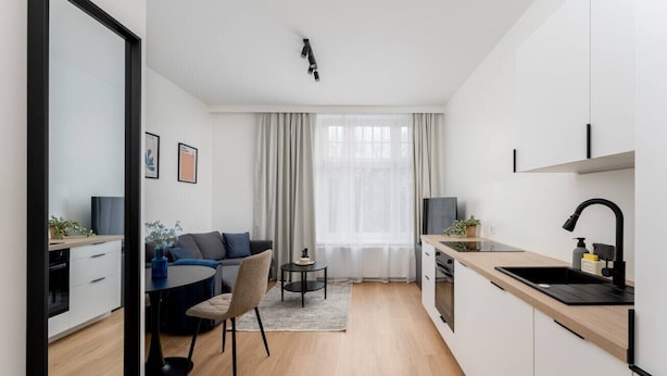 Et moderne køkken med spiseplads, en sofa og et stort vindue med gardiner.