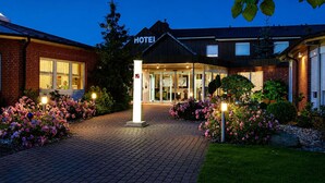 Hotellin sisäänkäynti, jossa on tiiliverhoiltu julkisivu, lasiovet ja kyltti, jossa lukee ”HOTELLI”.