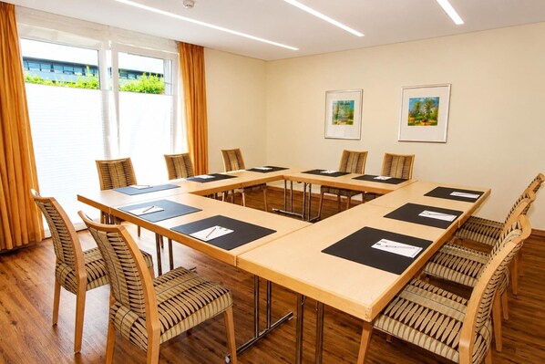 Ett konferensrum med ett långt bord, stolar och två inramade tavlor på väggen.