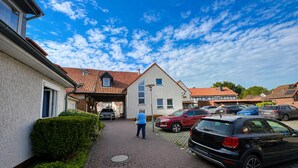 Une rue résidentielle bordée de maisons, avec un trottoir dallé et des voitures garées.