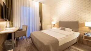 Une chambre d’hôtel avec un lit, un bureau, une chaise, une télévision et une lampe.